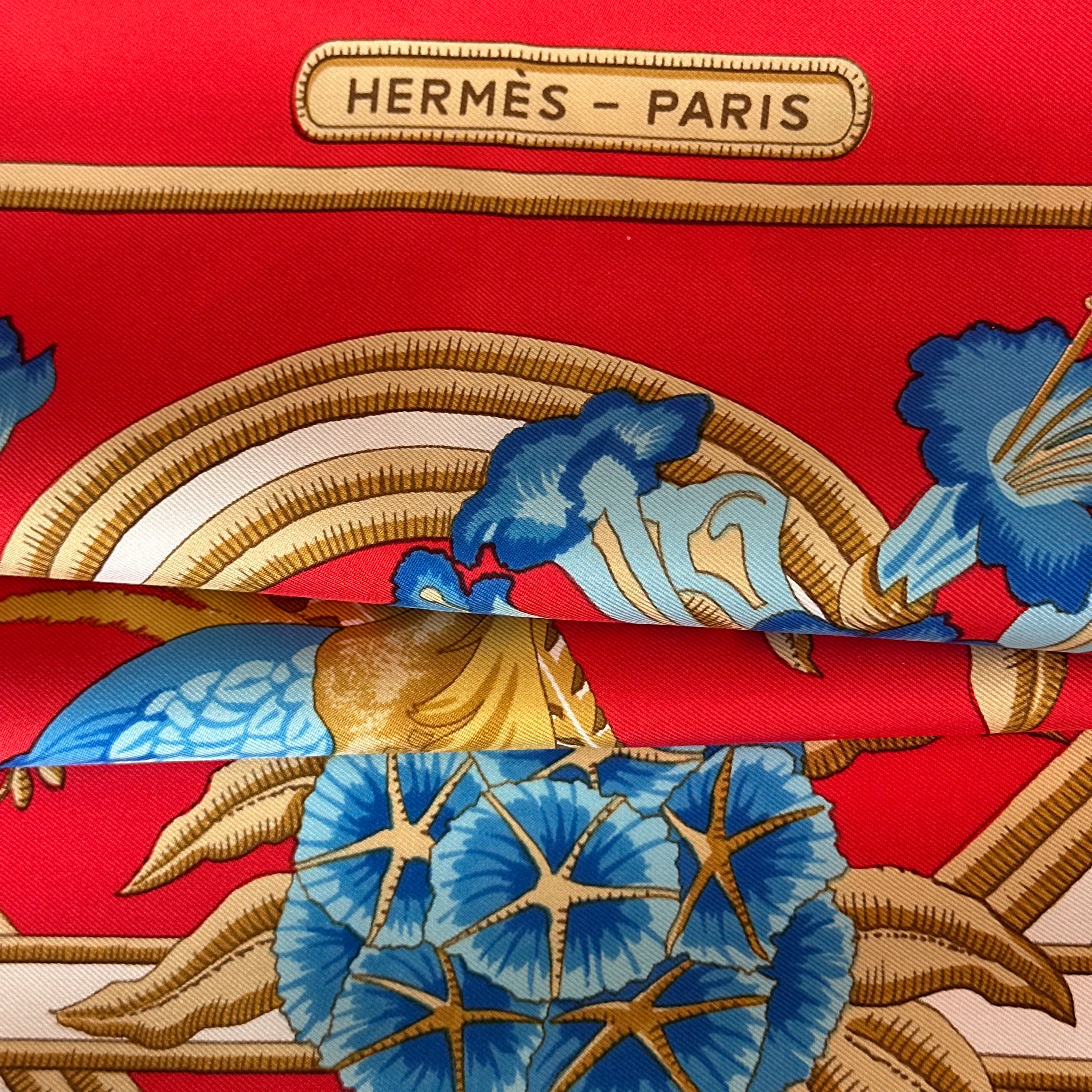 Détail de la bordure supérieure avec le logo "HERMÈS - PARIS" dans un cartouche doré et aperçu du roulotté main.