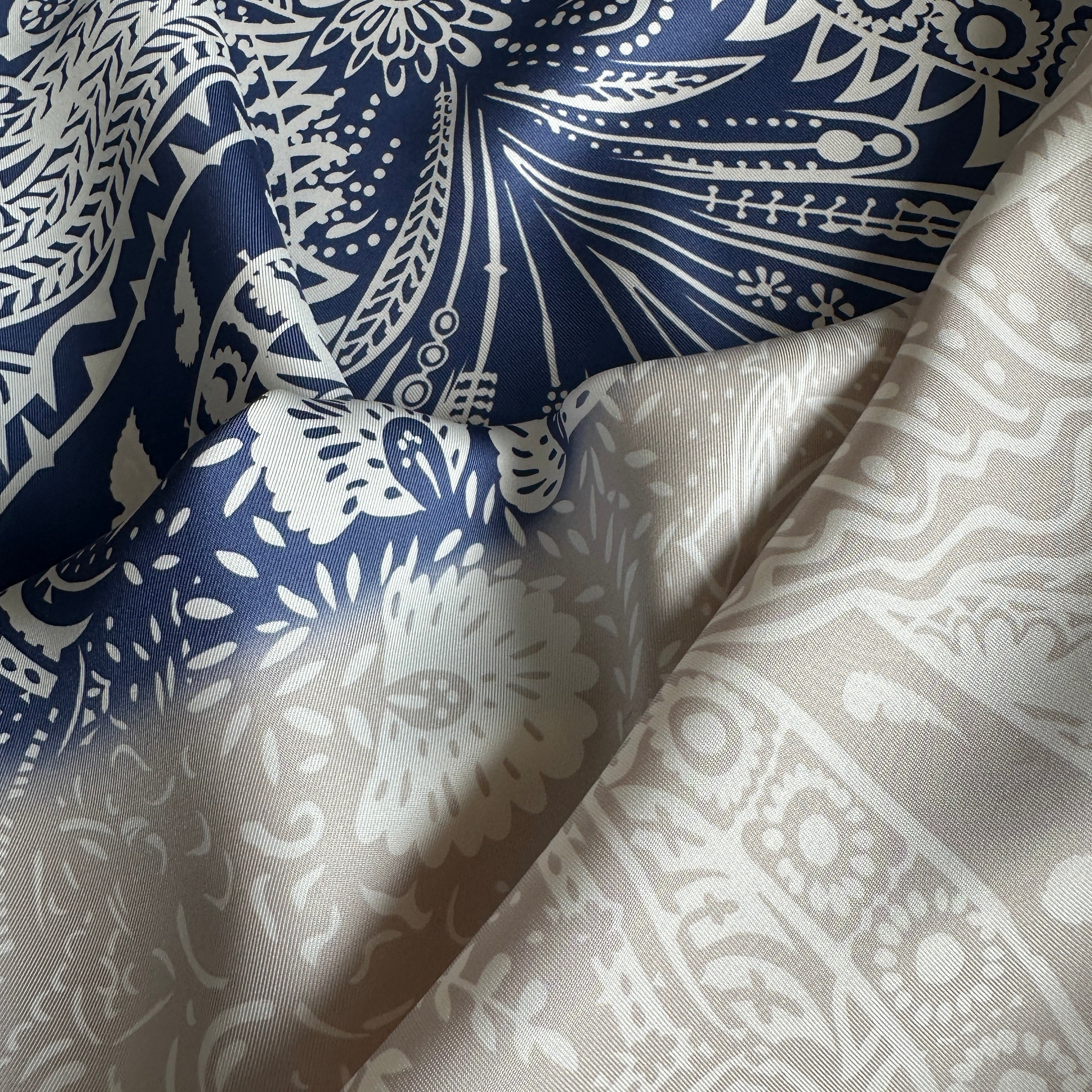 Foulard Hermès drapé pour montrer la texture du twill de soie et le jeu de contraste entre les sections bleu marine et gris clair.