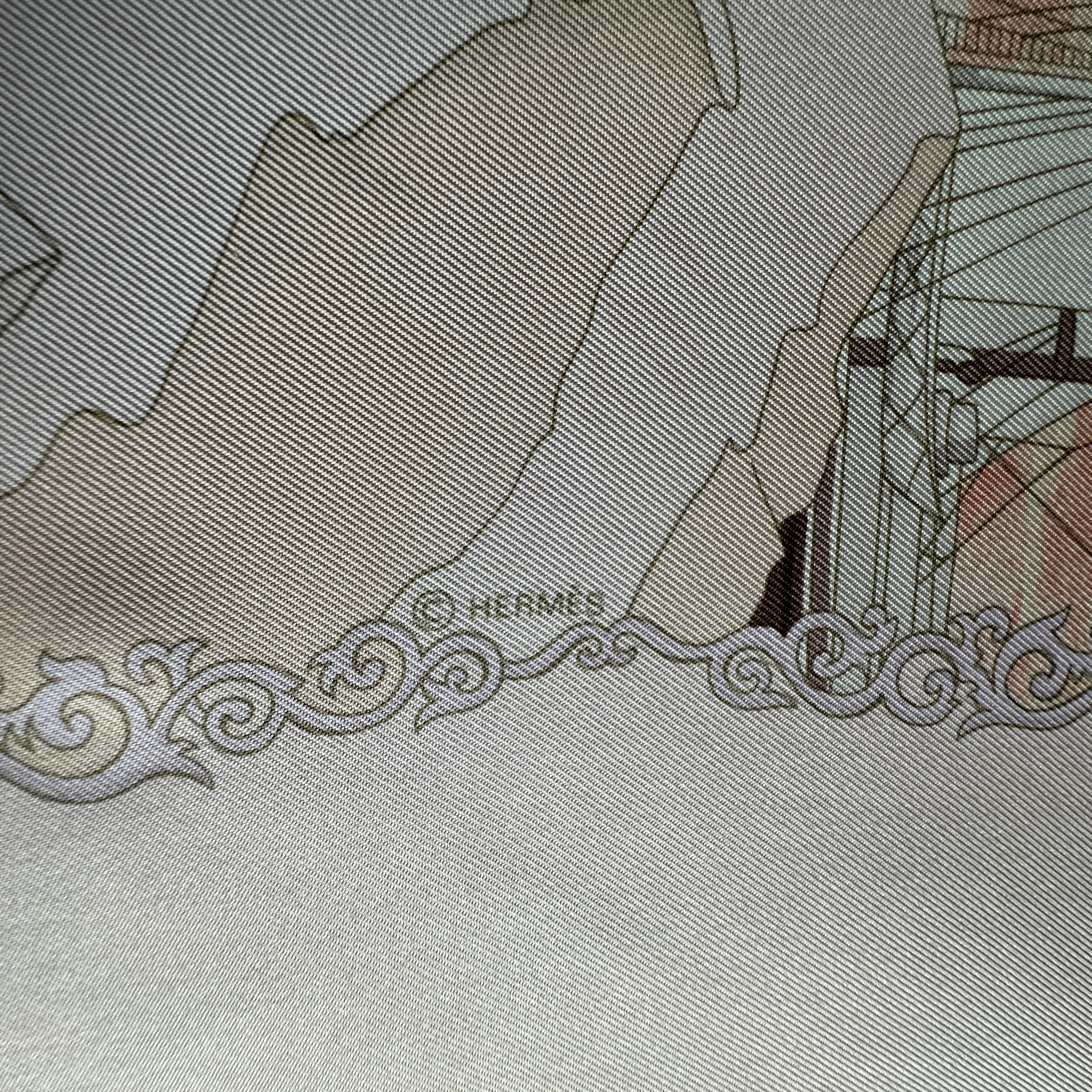 Détail du coin montrant le roulotté rose à la main et le copyright © Hermès discret.